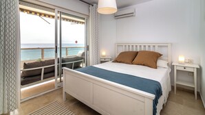 Ein Schlafzimmer mit Bett, Nachttischen, Meerblick und einem Balkon mit Stuhl.