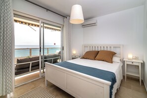 Ein Schlafzimmer mit Bett, Nachttischen, Meerblick und einem Balkon mit Stuhl.