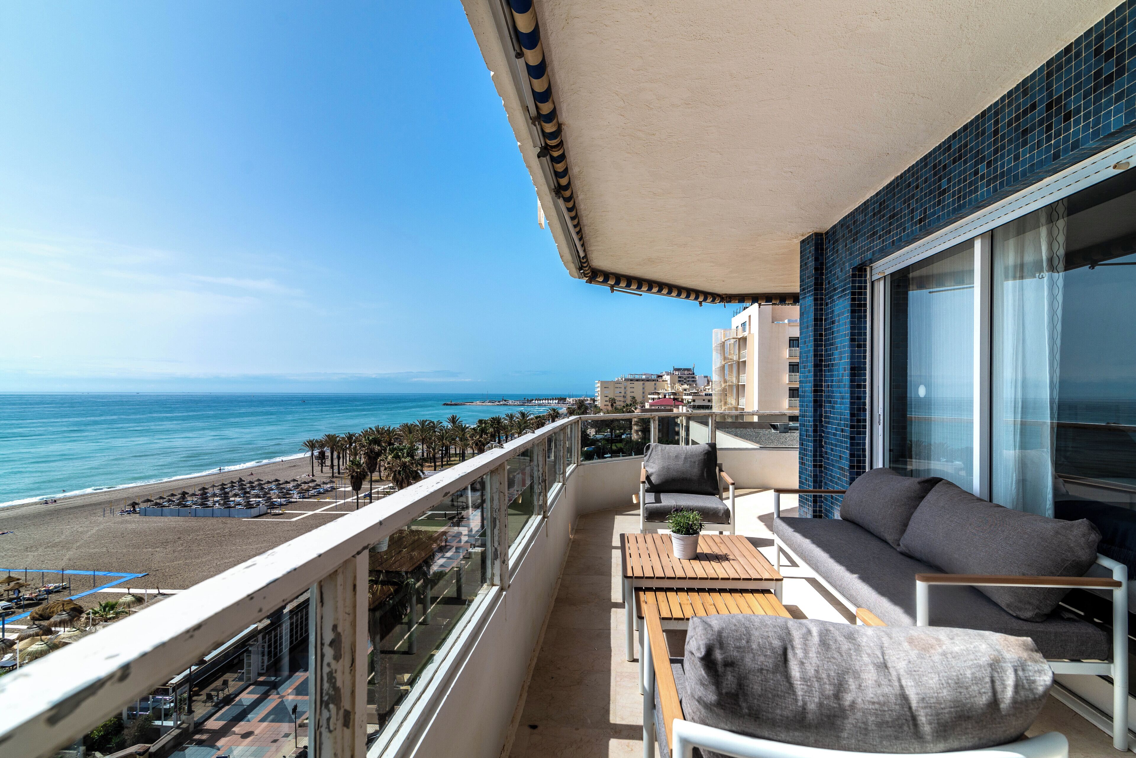 Ein Balkon mit Blick auf den Strand, eine Sitzecke, ein Tisch und ein Blumentopf.