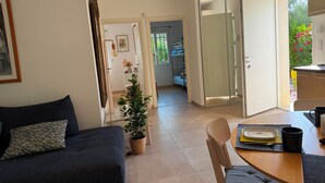A modern living room with a sofa, a dining table, and a potted plant.