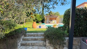 A stone staircase leading to a wooden deck, a swimming pool, and a building with a tiled roof.