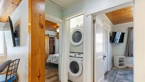 Une petite pièce équipée d’un lave-linge, d’un lit et d’un téléviseur.