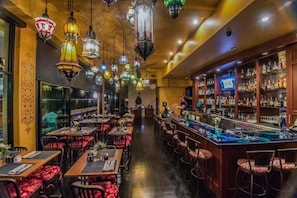 Ein Restaurant mit mehreren Tischen und Stühlen, einer Bar mit einer Theke und dekorativen Laternen.