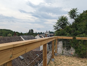 Ett träräcke på en balkong med utsikt över ett bostadsområde med hus och en slottsliknande byggnad i fjärran.