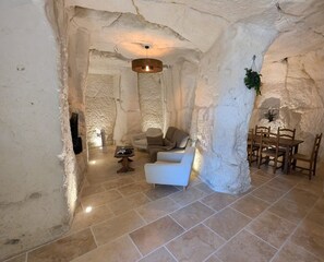 A stone-walled interior with a sofa, table, and dining set. - Le Secret de Saint-Jacques - Loches (Loches)