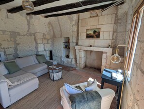 A rustic living room with exposed stone walls, a fireplace, a sofa, a coffee table, and a lamp. - Le Secret de Saint-Jacques - Loches (Loches)
