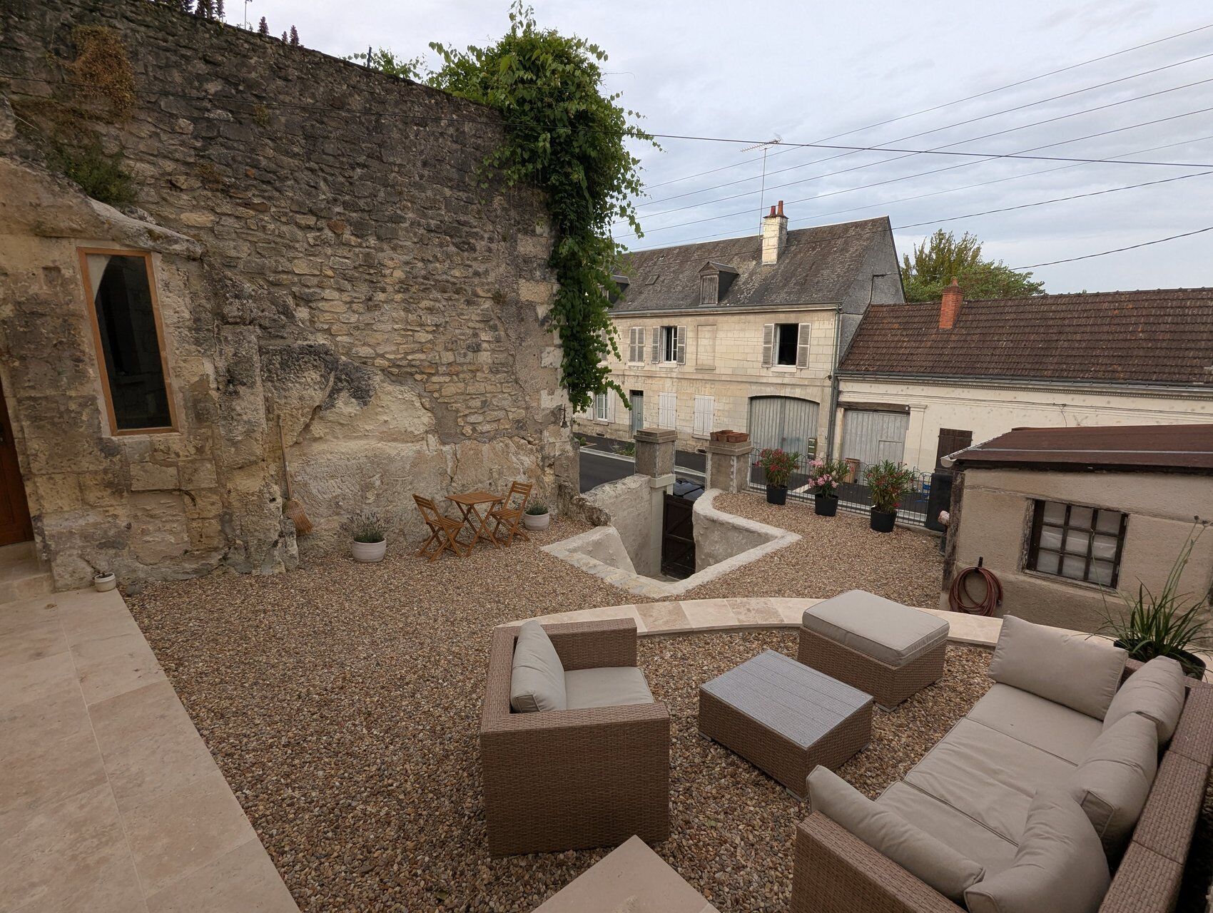 A courtyard with stone walls, outdoor furniture, and potted plants.