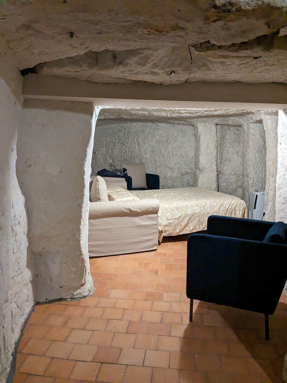 A room with a bed, a chair, and a tiled floor.