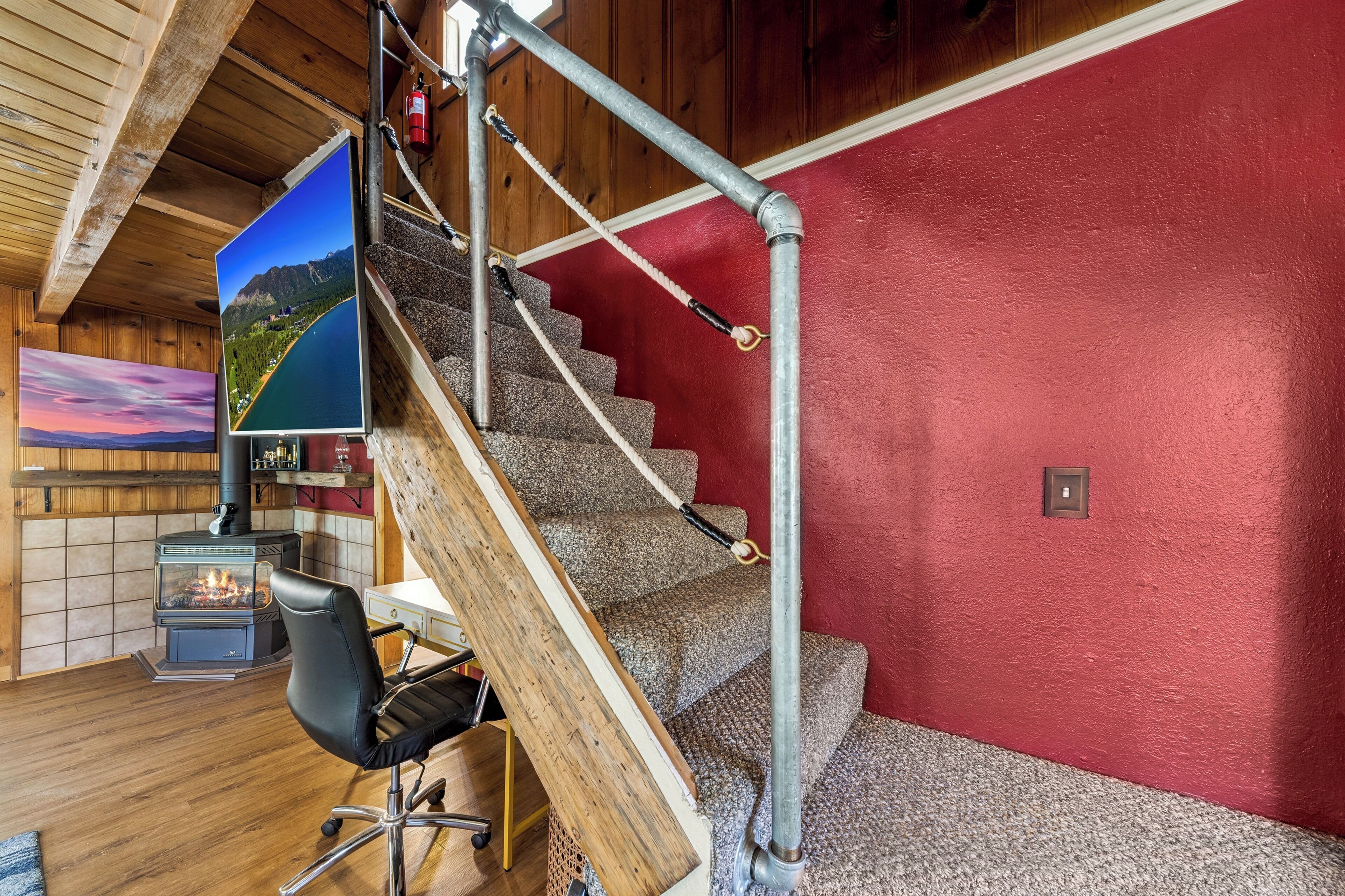 Un escalier avec un mur rouge, un plafond en bois et une cheminée.