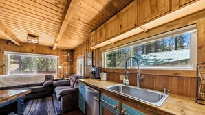 Ein Holzblock-Interieur mit Küche, Essbereich und großen Fenstern.