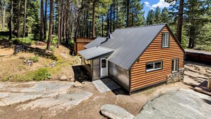 Eine Hütte mit geneigtem Dach, einer kleinen Veranda und einem Steinfundament.