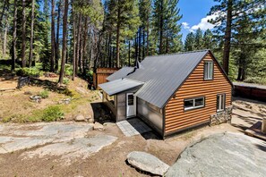 A cabin with a sloped roof, a small porch, and a stone foundation. - Sawmill Trail Tahoe Cabin (South Lake Tahoe)