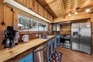 A wooden cabin kitchen with a coffee maker, sink, stove, and refrigerator. - Sawmill Trail Tahoe Cabin (South Lake Tahoe)