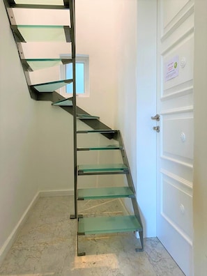 Una escala espiraltra amb graons de vidre que condueix a una plataforma.