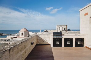 Eine Dachterrasse mit Meerblick, einer kleinen Kuppel und einem Grillplatz.