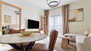 Ein modernes Wohnzimmer mit einem runden Esstisch, Ledersesseln, einer Couch, einem Flachbildfernseher und einem Bücherregal.