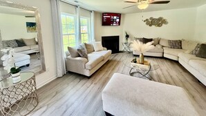 A living room with a fireplace, a ceiling fan, and a large mirror. - 5 bedroom spacious in quiet neighborhood (Greensboro)