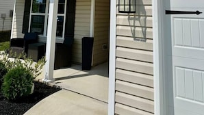 A two-story house with a front porch, a garage door, and a small garden area. - 5 bedroom spacious in quiet neighborhood (Greensboro)