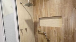 A shower area with a glass door, a showerhead, a handrail, and a tiled floor. - The perfect home for vacations, weekend getaways, family gatherings, and pets (Ixtapan De La Sal)