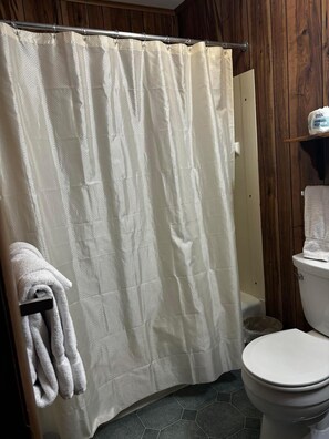 Ein Badezimmer mit Duschvorhang, Toilette und Handtuchhalter mit Handtüchern.