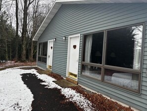 A single-story house with a front door, a large window, and a driveway with snow. - Cozy 1-bedroom hotel room, Hamilton - 313 Gilbreth (Hamilton)
