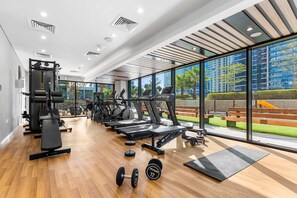 Ein modernes Fitnessstudio mit Trainingsgeräten, großen Fenstern und Blick auf einen Park.