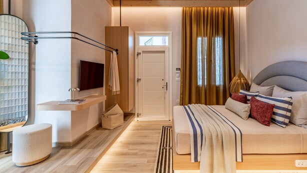 Ein modernes Schlafzimmer mit Bett, Fernseher, Holzboden und einer Tür.