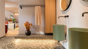 A modern bathroom with a wooden panel, a towel rack, a mirror, and a green sink. - Naxian Nest suites & houses (Naxos)