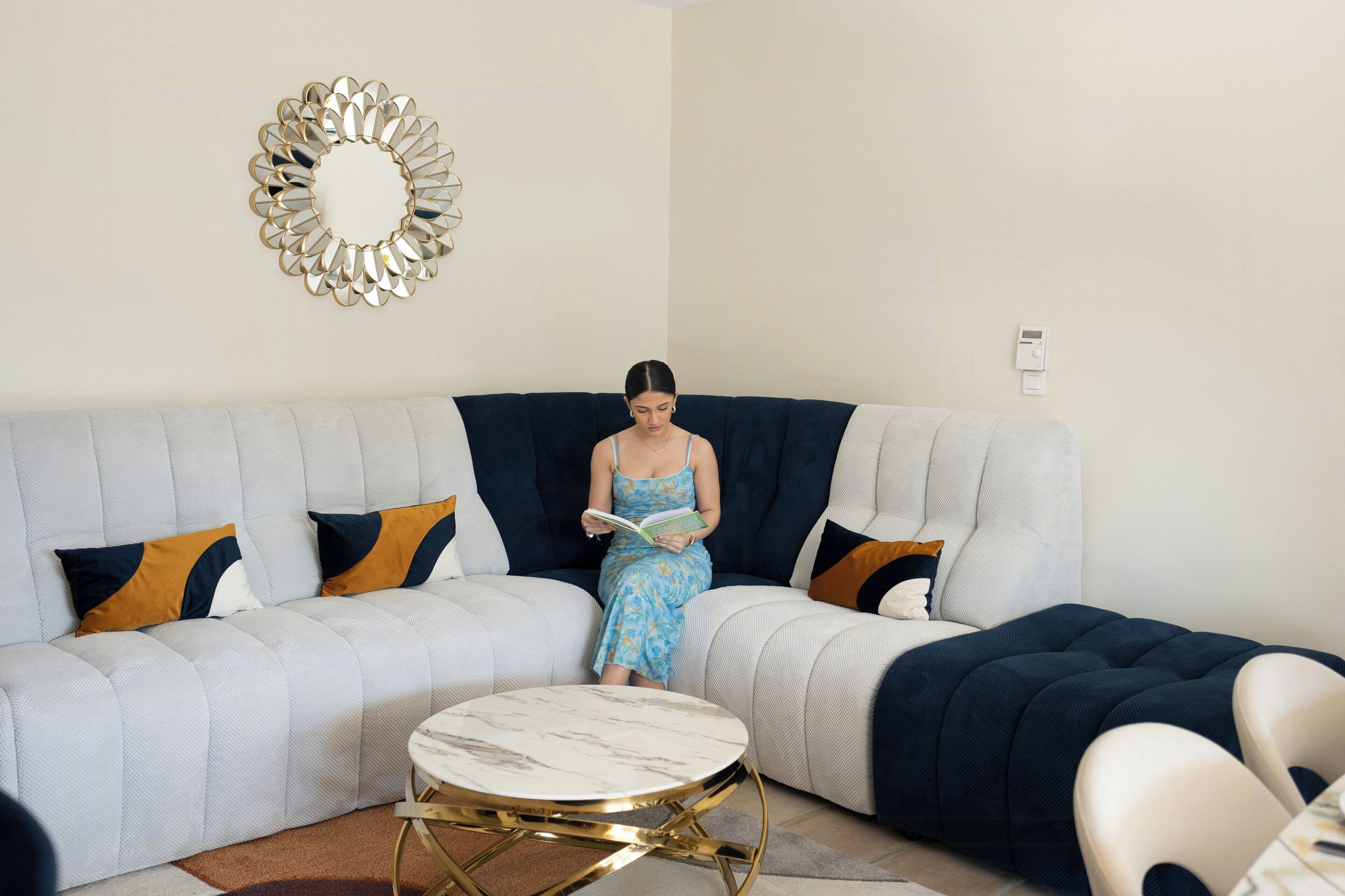 Ein Wohnzimmer mit einer Couch, einem runden Couchtisch und einem dekorativen Spiegel an der Wand.