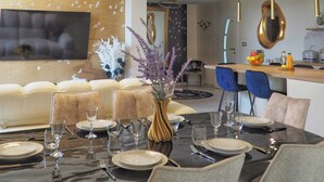 A modern dining area with a high ceiling, pendant lighting, a flat-screen TV, and a dining table set for six. - Family domaine with pool in the Camargue region (Arles)