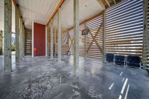 A spacious indoor area with a high ceiling, wooden beams, and a red brick wall. - Paradis Marin | Oceanfront + Private Pool (Oak Island)