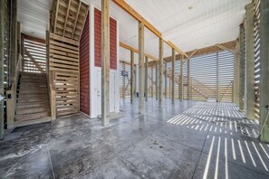 A spacious interior with a high ceiling and exposed wooden beams, a concrete floor, and a view through large windows. - Paradis Marin | Oceanfront + Private Pool (Oak Island)