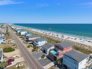 A coastal residential area with beachfront properties, a road, and beach umbrellas. - Paradis Marin | Oceanfront + Private Pool (Oak Island)