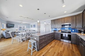 A spacious kitchen with wooden cabinets, a large island, and a built-in oven. - Paradis Marin | Oceanfront + Private Pool (Oak Island)
