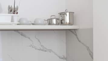 Una cocina con encimera blanca, un fregadero y un salpicadero de mármol.