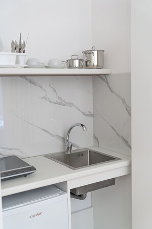 A kitchen with a white countertop, a sink, and a marble backsplash.