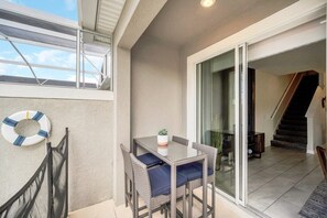 Een balkon met een tafel en stoelen, een reddingsboei en uitzicht op het interieur.