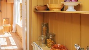 A kitchen with wooden cabinets, a window, and a shelf with jars and bowls. - 4 Star Holiday Home in Ebeltoft (Ebeltoft)