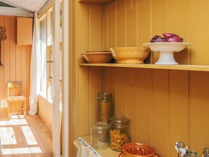 Eine Küche mit Holzschränken, einem Fenster und einem Regal mit Gläsern und Schüsseln.