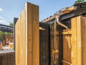 Eine hölzerne Außendusche mit Schlauch und Duschkopf.