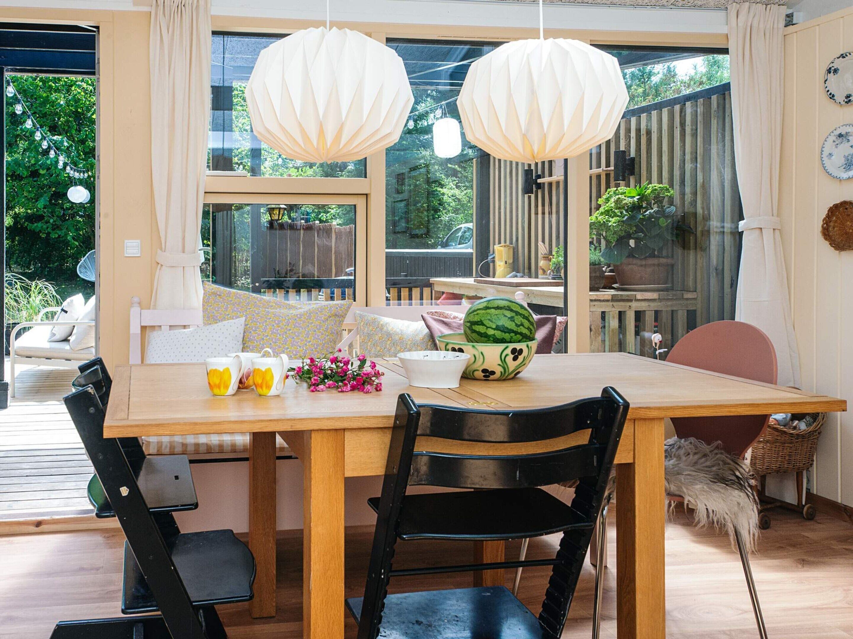 A dining area with a wooden table, black chairs, and a hanging paper lantern.