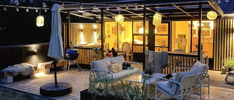 An outdoor patio area with a wooden deck, seating, and string lights.