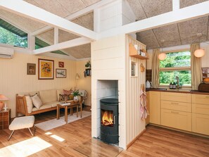 Una sala de estar acogedora con chimenea, piso de madera, un sofá y un comedor.