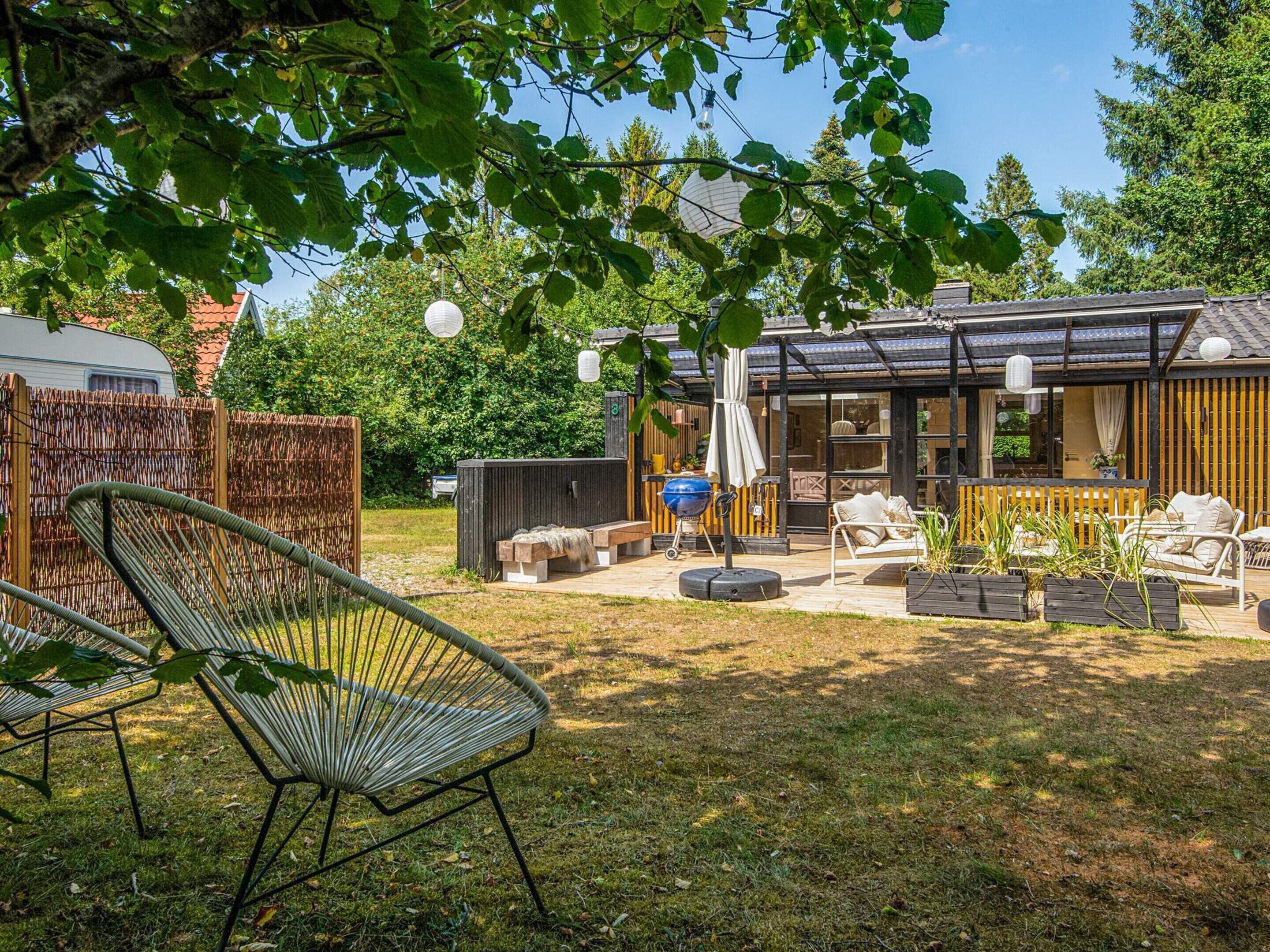 En baghave med grillområde, udendørs møbler og en overdækket terrasse.