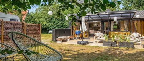 En baghave med grillområde, udendørs møbler og en overdækket terrasse.