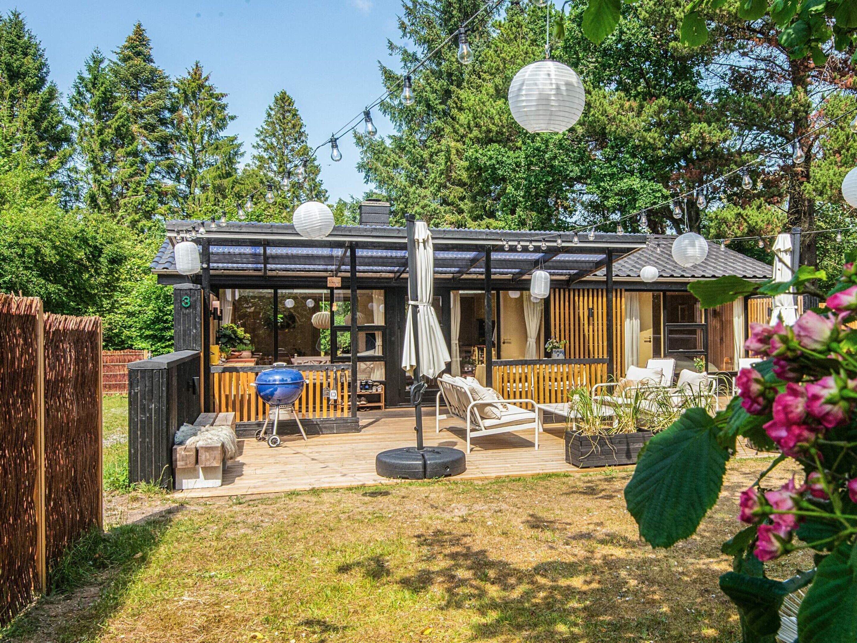A wooden deck with outdoor seating, a barbecue grill, and a covered patio area.
