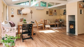 A spacious living room with a fireplace, wooden flooring, and a dining area with a table and chairs. - 4 Star Holiday Home in Ebeltoft (Ebeltoft)