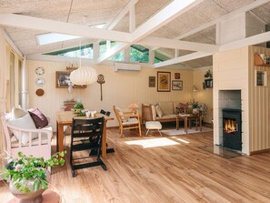 Ein großzügiges Wohnzimmer mit Kamin, Holzboden und einem Essbereich mit Tisch und Stühlen.