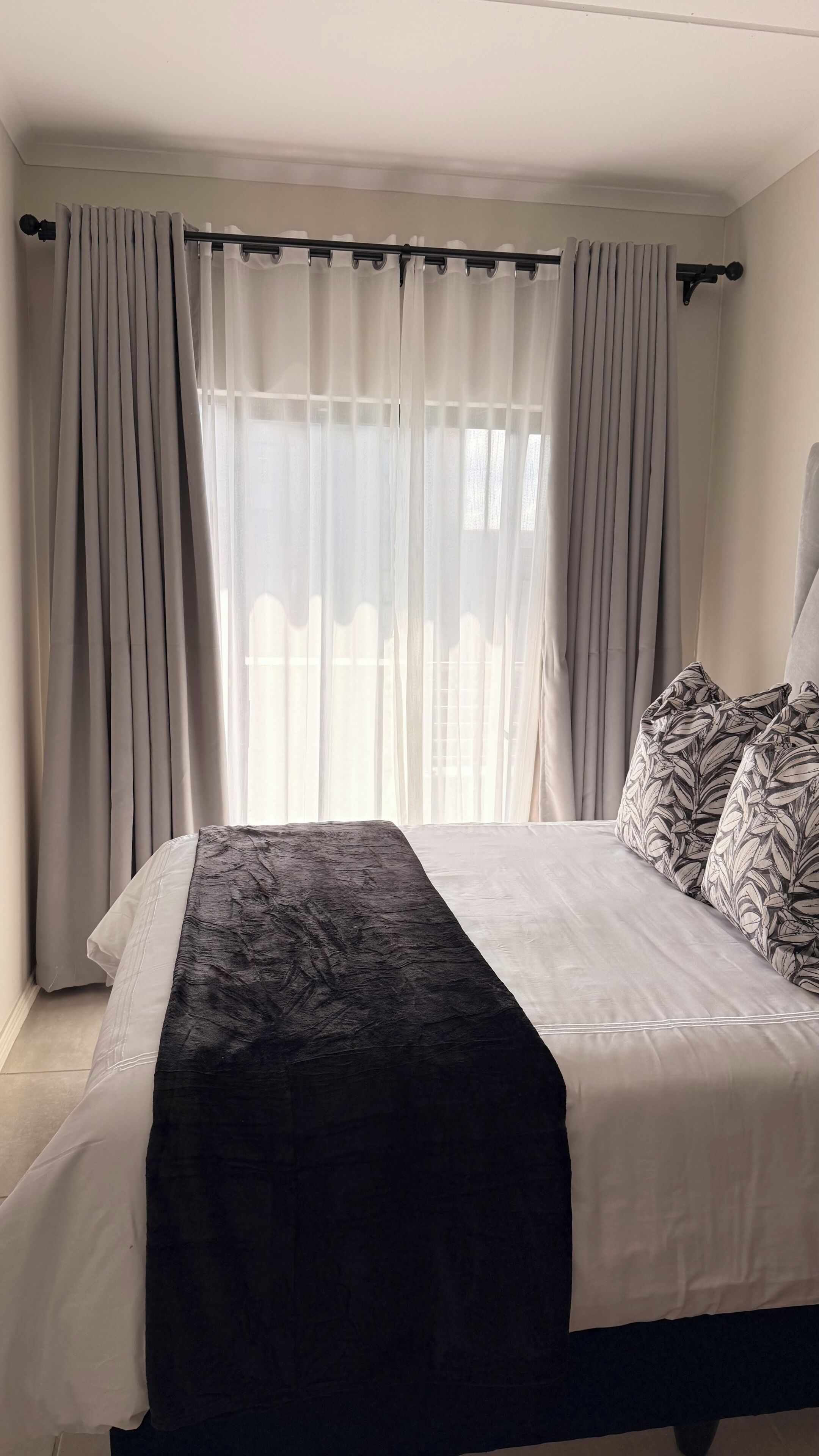 Ein Schlafzimmer mit Bett, Vorhängen und einem Fenster.