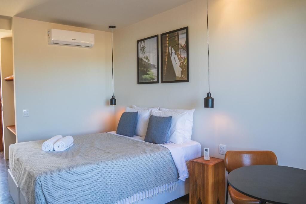 A hotel room with a bed, two wall-mounted lamps, a small table, and a chair.